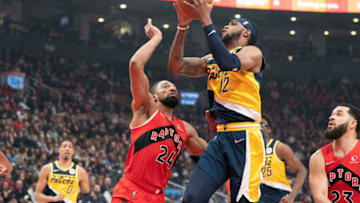 Mar 26, 2022; Toronto, Ontario, CAN; Indiana Pacers forward Oshae Brissett (12) drives to the basket against Toronto Raptors center Khem Birch (24) during the first quarter at Scotiabank Arena. Mandatory Credit: Nick Turchiaro-USA TODAY Sports