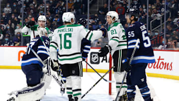 Mar 4, 2022; Winnipeg, Manitoba, CAN; Dallas Stars left wing Jason Robertson (21) celebrates his first period goal on Winnipeg Jets goaltender Connor Hellebuyck (37) with Dallas Stars center Joe Pavelski (16) at Canada Life Centre. Mandatory Credit: James Carey Lauder-USA TODAY Sports