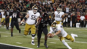 Sep 2, 2019; Louisville, KY, USA; Notre Dame Fighting Irish quarterback Ian Book (12) dives in for a touchdown against Louisville Cardinals linebacker C.J. Avery (9) during the second quarter at Cardinal Stadium. Mandatory Credit: Brian Spurlock-USA TODAY Sports