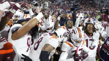 Nov 25, 2023; Charlottesville, Virginia, USA; Virginia Tech Hokies players celebrate with the Commonwealth Cup after their game against the Virginia Cavaliers at Scott Stadium. Mandatory Credit: Geoff Burke-USA TODAY Sports