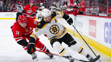 Oct 28, 2021; Raleigh, North Carolina, USA; Boston Bruins right wing David Pastrnak (88) tries to move the puck past Carolina Hurricanes defenseman Jaccob Slavin (74) during the third period at PNC Arena. Mandatory Credit: James Guillory-USA TODAY Sports