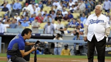 October 15, 2013; Los Angeles, CA, USA; Los Angeles Dodgers team photographer Jon SooHoo takes a picture of former manager Tommy Lasorda before the Dodgers play against the St. Louis Cardinals in game four of the National League Championship Series baseball game at Dodger Stadium. Mandatory Credit: Robert Hanashiro-USA TODAY Sports