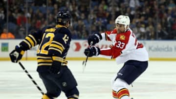 Oct 17, 2014; Buffalo, NY, USA; Buffalo Sabres right wing Brian Gionta (12) tries to block a shot by Florida Panthers defenseman Willie Mitchell (33) during the first period at First Niagara Center. Mandatory Credit: Timothy T. Ludwig-USA TODAY Sports