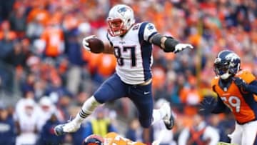 Jan 24, 2016; Denver, CO, USA; New England Patriots tight end Rob Gronkowski (87) leaps over Denver Broncos defensive back Shiloh Keo (33) in the second half in the AFC Championship football game at Sports Authority Field at Mile High. Mandatory Credit: Mark J. Rebilas-USA TODAY Sports