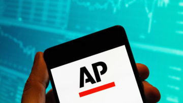 CHINA - 2023/02/15: In this photo illustration, the American news agency Associated Press (AP) logo seen displayed on a smartphone with an economic stock exchange index graph in the background. (Photo Illustration by Budrul Chukrut/SOPA Images/LightRocket via Getty Images)