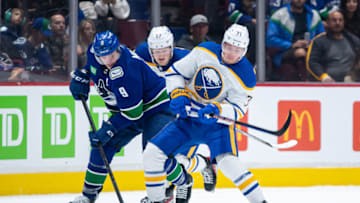 VANCOUVER, CANADA - OCTOBER 22: J.T. Miller #9 of the Vancouver Canucks and Victor Olofsson #71 of the Buffalo Sabres battle for the puck during the second period of their NHL game at Rogers Arena October 22, 2022 in Vancouver, British Columbia, Canada. Buffalo won 5-1. (Photo by Derek Cain/Getty Images)
