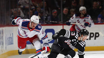NEWARK, NEW JERSEY - MARCH 22: Nico Hischier #13 of the New Jersey Devils and Adam Fox #23 of the New York Rangers collide during the second period at Prudential Center on March 22, 2022 in Newark, New Jersey. (Photo by Elsa/Getty Images)