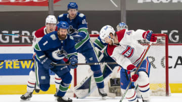 VANCOUVER, BC - MARCH 08: Joel Armia #40 of the Montreal Canadiens tries to control the puck while Jordie Benn #8 of the Vancouver Canucks skates out to challenge him during NHL hockey action at Rogers Arena on March 8, 2021 in Vancouver, Canada. Tyler Myers #57 of the Vancouver Canucks and Nick Suzuki #14 of the Montreal Canadiens battle for position in front of the net. (Photo by Rich Lam/Getty Images)
