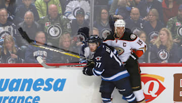 WINNIPEG, MB - MARCH 20: Chase De Leo #77 of the Winnipeg Jets and Ryan Getzlaf #15 of the Anaheim Ducks keep an eye on the play as they battle along the boards during third period action at the MTS Centre on March 20, 2016 in Winnipeg, Manitoba, Canada. (Photo by Jonathan Kozub/NHLI via Getty Images)