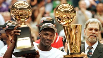 SALT LAKE CITY, UNITED STATES: In this 14 June 1998 file photo, Michael Jordan (L) holds the NBA Finals Most Valuable Player trophy and former Chicago Bulls head coach Phil Jackson holds the NBA champions Larry O'Brian trophy 14 June after winning game six of the NBA Finals with the Utah Jazz at the Delta Center in Salt Lake City, UT. The Bulls won the game 87-86 to take their sixth NBA championship. Jackson left the Bulls following the 1998 season and 12 January reports indicate that Jordan plans to announce his retirement at a 13 January news conference in Chicago. AFP PHOTO/FILES/Jeff HAYNES (Photo credit should read JEFF HAYNES/AFP via Getty Images)