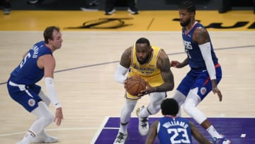 LOS ANGELES, CALIFORNIA - DECEMBER 22: LeBron James #23 of the Los Angeles Lakers looks to make a pass between Luke Kennard #5, Paul George #13 and Lou Williams #23 of the LA Clippers during a 116-109 Clippers win in the season opening game at Staples Center on December 22, 2020 in Los Angeles, California. NOTE TO USER: User expressly acknowledges and agrees that, by downloading and or using this photograph, User is consenting to the terms and conditions of the Getty Images License Agreement. (Photo by Harry How/Getty Images)