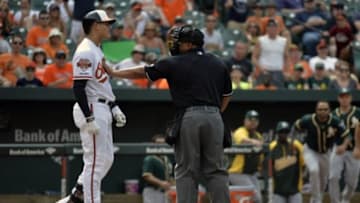 Jun 8, 2014; Baltimore, MD, USA; Baltimore Orioles third baseman Manny Machado (13) is held back by home plate umpire Adrian Johnson after Machado (R) takes exception to an inside pitch during the eighth inning at Oriole Park at Camden Yards. The Athletics won 11-1. Mandatory Credit: Joy R. Absalon-USA TODAY Sports