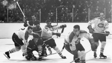 Canadian professional hockey players and Montreal Canadiens teammates Doug Harvey (#2) (1924 - 1989) and Dickie Moore (#12) attempt to block an opposing player from the Toronto Maple Leafs as a Canadiens player skates away with the puck during a game, late 1950s or early 1960s. (Photo by Robert Riger/Getty Images)