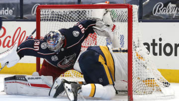 May 5, 2021; Columbus, Ohio, USA; Columbus Blue Jackets goalie Elvis Merzlikins (90) makes a save as Nashville Predators center Yakov Trenin (13) crashes into net during the second period at Nationwide Arena. Mandatory Credit: Russell LaBounty-USA TODAY Sports