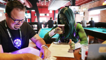 SAN DIEGO, CA - JULY 20: A cosplayer (R) dressed as She-Hulk drinks a beer outside San Diego Comic-Con on July 20, 2018 in San Diego, California. More than 100,000 attendees are expected at the annual comic and entertainment convention. (Photo by Mario Tama/Getty Images)