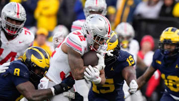 Nov 25, 2023; Ann Arbor, Michigan, USA; Ohio State Buckeyes running back TreVeyon Henderson (32) runs through Michigan Wolverines defensive end Derrick Moore (8) and linebacker Ernest Hausmann (15) during the NCAA football game at Michigan Stadium. Ohio State lost 30-24.
