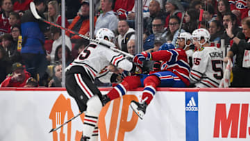 MONTREAL, CANADA - OCTOBER 14: Jarred Tinordi #25 of the Chicago Blackhawks pushes Kirby Dach #77 of the Montreal Canadiens into the Blackhawks bench during the first period at the Bell Centre on October 14, 2023 in Montreal, Quebec, Canada. (Photo by Minas Panagiotakis/Getty Images)