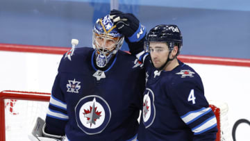 Apr 5, 2021; Winnipeg, Manitoba, CAN; Winnipeg Jets goaltender Connor Hellebuyck (37) and Winnipeg Jets defenseman Neal Pionk (4) celebrate their win over the Ottawa Senators at Bell MTS Place. Mandatory Credit: James Carey Lauder-USA TODAY Sports