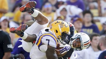 Sep 19, 2015; Baton Rouge, LA, USA; Auburn Tigers defensive back Trey Matthews (28) jumps over Louisiana State Tigers running back Leonard Fournette (7) to try to get the ball loose in the second half at Tiger Stadium. Fournette kept running to score his second touchdown of the game. Mandatory Credit: Erich Schlegel-USA TODAY Sports