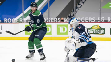 VANCOUVER, BC - FEBRUARY 19: JT Miller #9 of the Vancouver Canucks tries to redirect the puck past goalie Laurent Brossoit #30 of the Winnipeg Jets during NHL hockey action at Rogers Arena on February 19, 2021 in Vancouver, Canada. (Photo by Rich Lam/Getty Images)