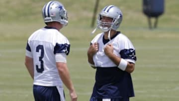 Jun 17, 2014; Dallas, TX, USA; Dallas Cowboys quarterback Tony Romo (9) smiles as he hides jersey number 7 he borrowed from Caleb Hanie (not pictured) as he talks to Brandon Weeden (3) during minicamp at Cowboys headquarters at Valley Ranch. Mandatory Credit: Matthew Emmons-USA TODAY Sports