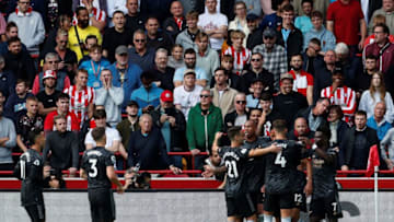 Brentford fans react as Arsenal's French defender William Saliba is mobbed by teammates after scoring the opening goal during the English Premier League football match between Brentford and Arsenal at the Gtech Community Stadium in London on September 18, 2022. - - RESTRICTED TO EDITORIAL USE. No use with unauthorized audio, video, data, fixture lists, club/league logos or 'live' services. Online in-match use limited to 120 images. An additional 40 images may be used in extra time. No video emulation. Social media in-match use limited to 120 images. An additional 40 images may be used in extra time. No use in betting publications, games or single club/league/player publications. (Photo by Ian Kington / AFP) / RESTRICTED TO EDITORIAL USE. No use with unauthorized audio, video, data, fixture lists, club/league logos or 'live' services. Online in-match use limited to 120 images. An additional 40 images may be used in extra time. No video emulation. Social media in-match use limited to 120 images. An additional 40 images may be used in extra time. No use in betting publications, games or single club/league/player publications. / RESTRICTED TO EDITORIAL USE. No use with unauthorized audio, video, data, fixture lists, club/league logos or 'live' services. Online in-match use limited to 120 images. An additional 40 images may be used in extra time. No video emulation. Social media in-match use limited to 120 images. An additional 40 images may be used in extra time. No use in betting publications, games or single club/league/player publications. (Photo by IAN KINGTON/AFP via Getty Images)
