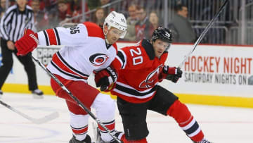 Dec 29, 2015; Newark, NJ, USA; Carolina Hurricanes defenseman Ron Hainsey (65) and New Jersey Devils right wing Lee Stempniak (20) battle for the puck during the second period at Prudential Center. Mandatory Credit: Ed Mulholland-USA TODAY Sports