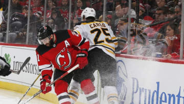 NEWARK, NJ - DECEMBER 31: Kyle Palmieri #21 of the New Jersey Devils and Brandon Carlo #25 of the Boston Bruins battle against the boards during the game at the Prudential Center on December 31, 2019 in Newark, New Jersey. (Photo by Andy Marlin/NHLI via Getty Images)
