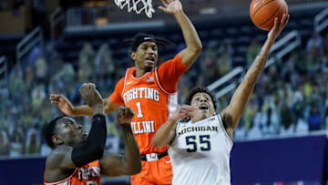 Michigan guard Eli Brooks (55) makes a layup against Illinois guard Trent Frazier (1) and center Kofi Cockburn (21) during the first half Tuesday, March 2, 2021, at the Crisler Center in Ann Arbor.