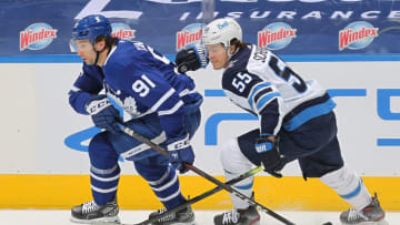 TORONTO, ON - MARCH 13: Mark Scheifele #55 of the Winnipeg Jets is about to draw a penalty for tripping John Tavares #91 of the Toronto Maple Leafs during an NHL game at Scotiabank Arena on March 13, 2021 in Toronto, Ontario, Canada. The Jets defeated the Maple Leafs 5-2. (Photo by Claus Andersen/Getty Images)
