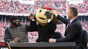 Nov 26, 2016; Columbus, OH, USA; Former Ohio State Buckeyes players Orlando Pace (l) and Kirk Herbstreit (r) laugh as ESPN College Gameday host Lee Corso dons the head of Brutus Buckeye, signifying his pick for the game against the Michigan Wolverines at Ohio Stadium. Ohio State won the game 30-27 in double overtime. Mandatory Credit: Greg Bartram-USA TODAY Sports
