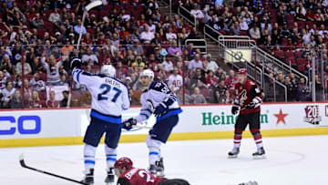 Nov 10, 2016; Glendale, AZ, USA; Winnipeg Jets left wing Nikolaj Ehlers (27) celebrates with center Mark Scheifele (55) as defenseman Oliver Ekman-Larsson (23) lays on the ice during the third period at Gila River Arena. Mandatory Credit: Matt Kartozian-USA TODAY Sports