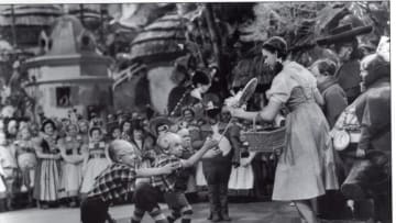 1939: Jerry Maren, playing a Lollipop Guild Member, presents Judy Garland with a lollipop in the film "The Wizard of Oz."