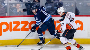 WINNIPEG, MB - MARCH 23: Andrew Copp #9 of the Winnipeg Jets plays the puck along the boards as Hampus Lindholm #47 of the Anaheim Ducks gives chase during second period action at the Bell MTS Place on March 23, 2018 in Winnipeg, Manitoba, Canada. The Jets defeated the Ducks 3-2 in overtime. (Photo by Jonathan Kozub/NHLI via Getty Images)