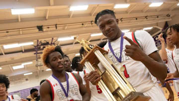 Highland Park seniors Ketraleus Aldridge (1) and Tre Richardson (0) celebrate with the trophy for the Topeka Invitational Tournament after defeating Lawrence 58-47 Saturday at Topeka West.