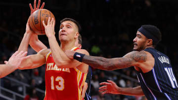 ATLANTA, GEORGIA - DECEMBER 22: Bogdan Bogdanovic #13 of the Atlanta Hawks draws a foul as he drives against Gary Harris #14 of the Orlando Magic during the first half at State Farm Arena on December 22, 2021 in Atlanta, Georgia. NOTE TO USER: User expressly acknowledges and agrees that, by downloading and or using this photograph, User is consenting to the terms and conditions of the Getty Images License Agreement. (Photo by Kevin C. Cox/Getty Images)