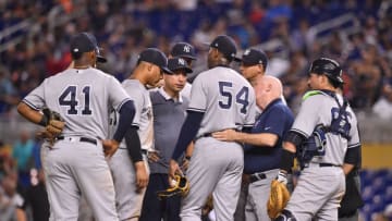 MIAMI, FL - AUGUST 21: Teammates and trainers visit with Aroldis Chapman #54 of the New York Yankees on the mound after Chapman was injured throwing a pitch in the twelfth inning against the Miami Marlins at Marlins Park on August 21, 2018 in Miami, Florida. (Photo by Mark Brown/Getty Images)
