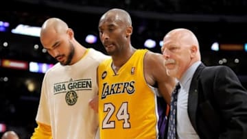 April 12, 2013; Los Angeles, CA, USA; Los Angeles Lakers trainer Gary Vitti and center Robert Sacre (50) help shooting guard Kobe Bryant (24) as leaves the game in the fourth quarter against the Golden State Warriors at the Staples Center. Bryant suffered a torn Achilles tendon. He under went surgery April 13 and is expected to miss six to nine months. Mandatory Credit: Jayne Kamin-Oncea-USA TODAY Sports