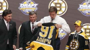 Jun 24, 2016; Buffalo, NY, USA; Charles McAvoy puts on a team jersey after being selected as the number fourteen overall draft pick by the Boston Bruins in the first round of the 2016 NHL Draft at the First Niagra Center. Mandatory Credit: Timothy T. Ludwig-USA TODAY Sports