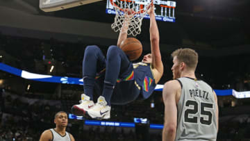 SAN ANTONIO, TX - DECEMBER 11: Nikola Jokic #15 of the Denver Nuggets hanks onto the rim as Keldon Johnson #3 of the San Antonio Spurs and Jakob Poeltl #25 can only watch in the second half at AT&T Center on December 11, 2021 in San Antonio, Texas. NOTE TO USER: User expressly acknowledges and agrees that , by downloading and or using this photograph, User is consenting to the terms and conditions of the Getty Images License Agreement. (Photo by Ronald Cortes/Getty Images)
