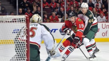 Mar 5, 2013; Chicago, IL, USA; Chicago Blackhawks center Jonathan Toews (19) is defended by Minnesota Wild defenseman Justin Falk (44) as he shoots the puck on goalie Darcy Kuemper (35) during the third period at the United Center. The Chicago Blackhawks beat the Minnesota Wild 5-3. The Blackhawks set an NHL record for scoring at least one point in 23 consecutive games to open a season. Mandatory Credit: Rob Grabowski-USA TODAY Sports