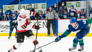 VANCOUVER, BC - APRIL 22: Olli Juolevi #48 of the Vancouver Canucks tries to defend against the shot of Shane Pinto #57 of the Ottawa Senators during NHL action at Rogers Arena on April 22, 2021 in Vancouver, Canada. (Photo by Rich Lam/Getty Images)
