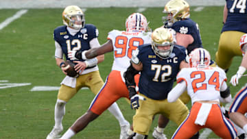 Dec 19, 2020; Charlotte, NC, USA; Notre Dame Fighting Irish quarterback Ian Book (12) looks to pass as Clemson Tigers defensive end Myles Murphy (98) defends in the first quarter at Bank of America Stadium. Mandatory Credit: Bob Donnan-USA TODAY Sports