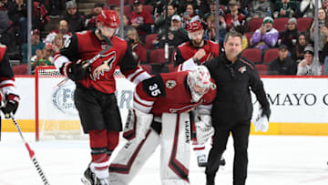 GLENDALE, ARIZONA - DECEMBER 19: Goalie Darcy Kuemper #35 of the Arizona Coyotes is assisted off the ice by teammate Jakob Chychrun #6 and Coyotes head athletic trainer Dave Zenobi after suffering an injury during the third period of the NHL hockey game against the Minnesota Wild at Gila River Arena on December 19, 2019 in Glendale, Arizona. (Photo by Norm Hall/NHLI via Getty Images)