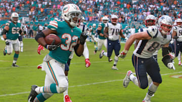 MIAMI GARDENS, FL - DECEMBER 9: Miami Dolphins' Kenyan Drake (32) heads to the end zone as the Patriots' Rob Gronkowski (87, right) pursues, but can't stop him from scoring the game-winning touchdown on the last play of the game. Miami stunned New England 34-33. The New England Patriots visit the Miami Dolphins in a regular season NFL football game at Hard Rock Stadium in Miami Gardens, FL on Dec. 9, 2018. (Photo by Jim Davis/The Boston Globe via Getty Images)