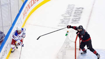 Tony DeAngelo #77 of the New York Rangers holds on to the puck as he is checked by Warren Foegele #13 of the Carolina Hurricanes. (Photo by Andre Ringuette/Getty Images)