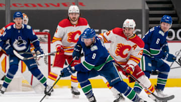 VANCOUVER, BC - FEBRUARY 13: JT Miller #9 of the Vancouver Canucks skates with the puck while being checked by Sean Monahan #23 of the Calgary Flames during NHL hockey action at Rogers Arena on February 13, 2021 in Vancouver, Canada. Goalie Jacob Markstrom #25 of the Calgary Flames, Rasmus Andersson #4 along with Elias Pettersson #40 of the Vancouver Canucks and Brock Boeser #6 look on during the play. (Photo by Rich Lam/Getty Images)