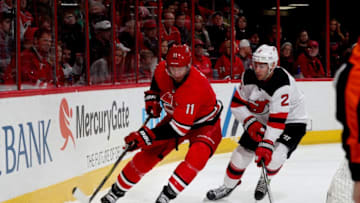 RALEIGH, NC - MARCH 2: Jordan Staal #11 of the Carolina Hurricanes plays a loose puck behind the net and controls it away from John Moore #2 of the New Jersey Devils during an NHL game on March 2, 2018 at PNC Arena in Raleigh, North Carolina. (Photo by Gregg Forwerck/NHLI via Getty Images)