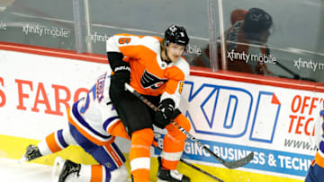 PHILADELPHIA, PENNSYLVANIA - JANUARY 30: Travis Sanheim #6 of the Philadelphia Flyers passes the pucks as Cal Clutterbuck #15 of the New York Islanders defends at Wells Fargo Center on January 30, 2021 in Philadelphia, Pennsylvania. (Photo by Tim Nwachukwu/Getty Images)