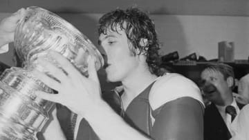 Philadelphia Flyers center Bobby Clarke drinks champagne from the Stanley Cup in their locker room after winning the sixth and final game of the series 1-0. The Flyers are the first expansion club to win the finals of the Cub Series.